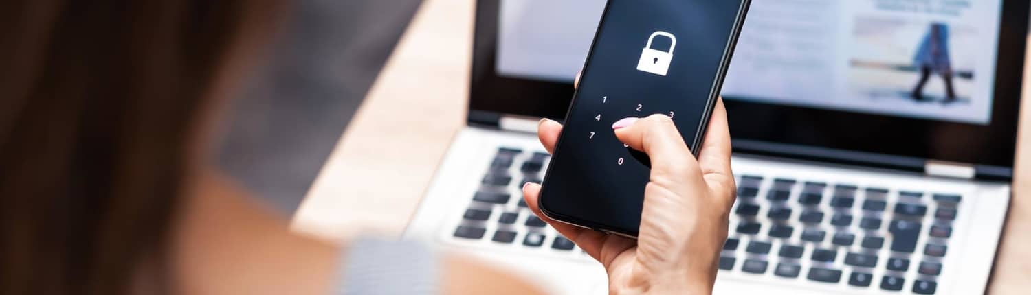 Do's and Don'ts of 2FA December Blog 2 woman uses two-factor authentication on mobile device while using laptop